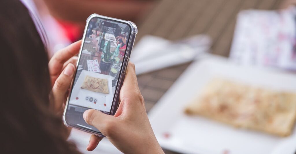 Close-up of a woman photographing a meal at a restaurant using a smartphone.