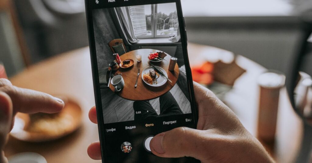 Smartphone captures a well-dressed table with food, showcasing modern dining indoors.