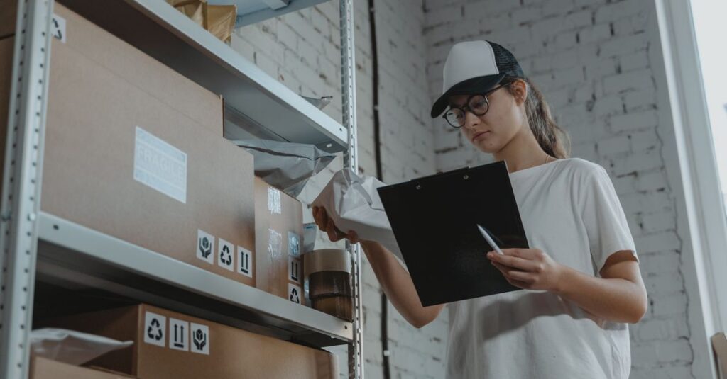 Warehouse worker organizing packages on shelf with clipboard.