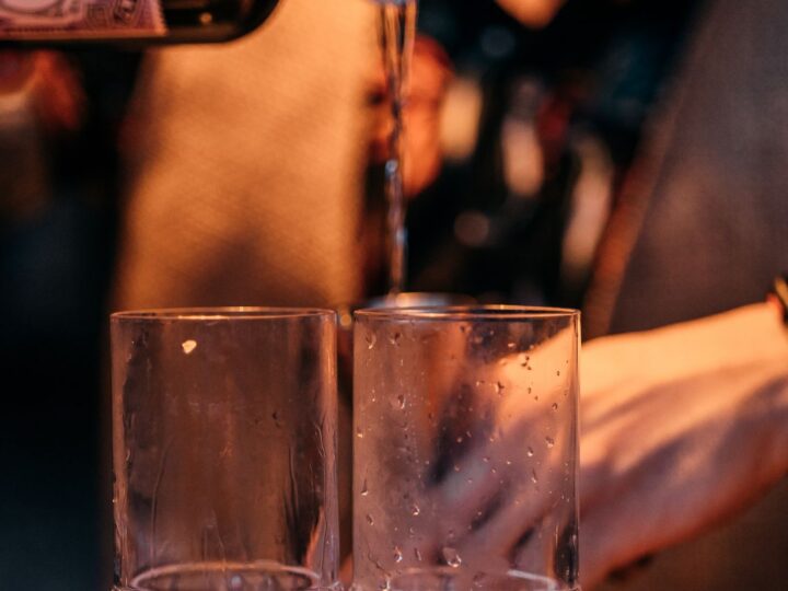 Bartender servindo bebida em copos no balcão do bar