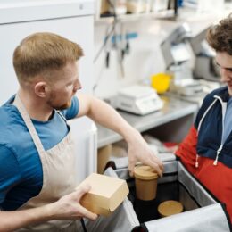Entregador recebendo pedido de delivery embalado na cozinha do restaurante