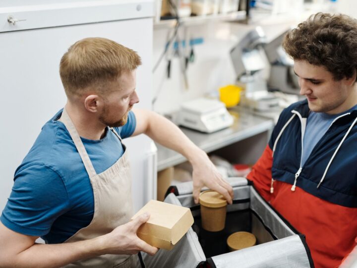 Entregador recebendo pedido de delivery embalado na cozinha do restaurante