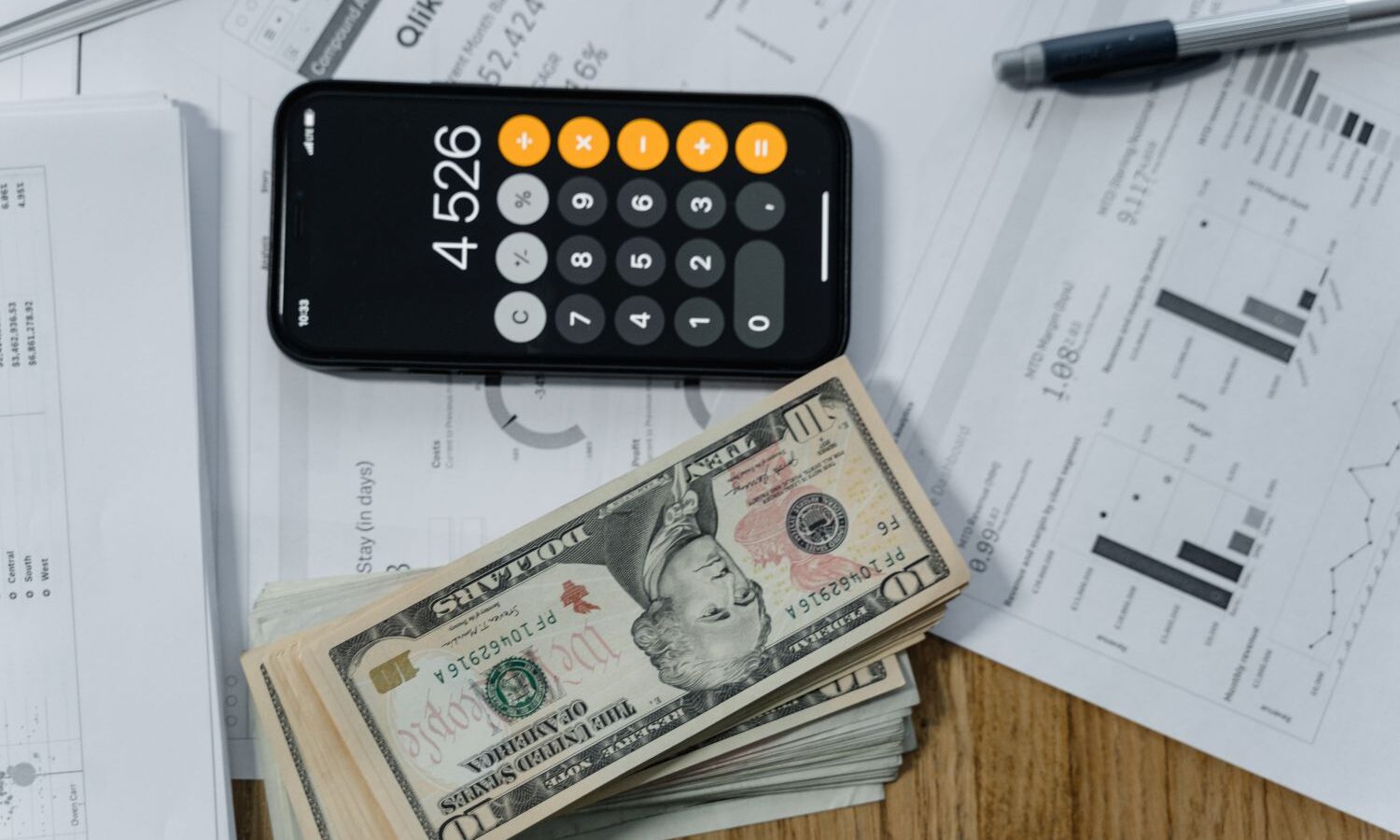 Dinheiro e calculadora sobre relatório para calcular o retorno do investimento
