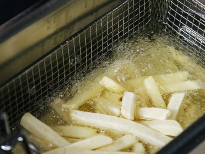 Batatas fritando em fritadeira de aço inox